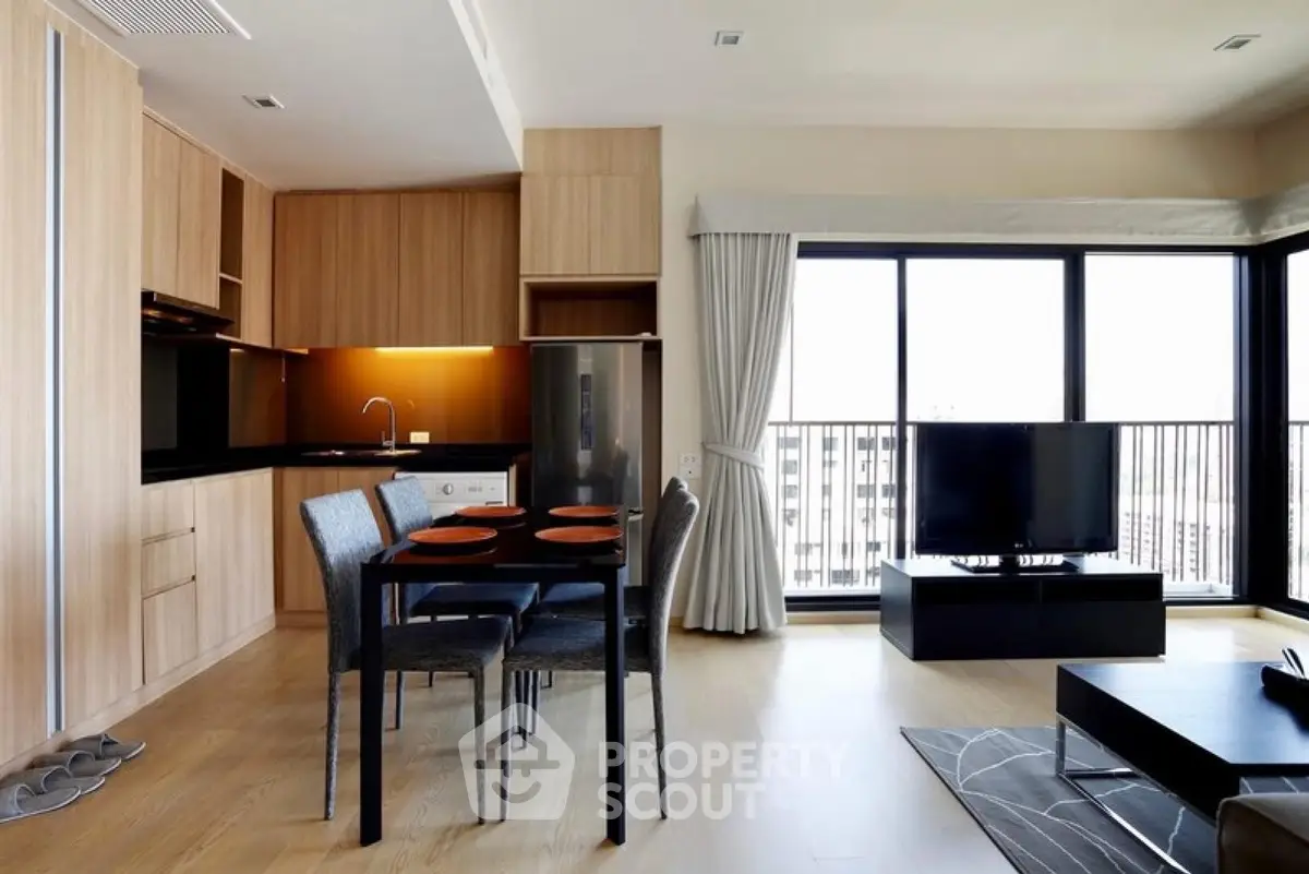 Modern open-plan living room with kitchen, dining area, and large windows with city view.