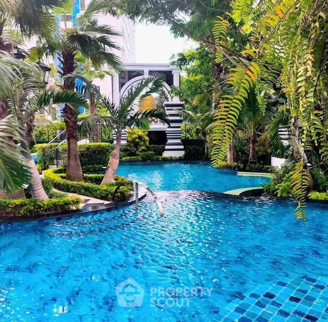 Luxurious tropical pool surrounded by lush greenery in a modern residential complex.