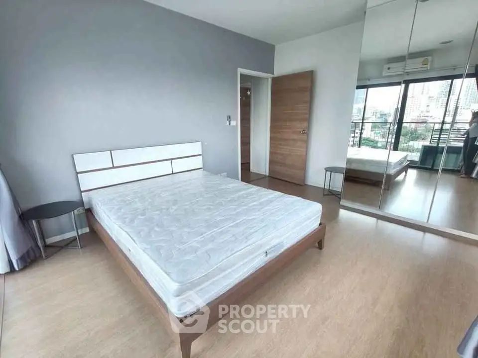 Spacious bedroom with city view and mirrored wardrobe in modern apartment