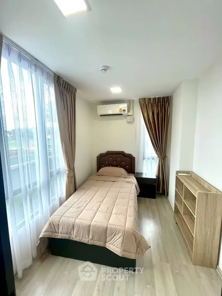 Cozy bedroom with single bed, large windows, and modern decor in a bright apartment.