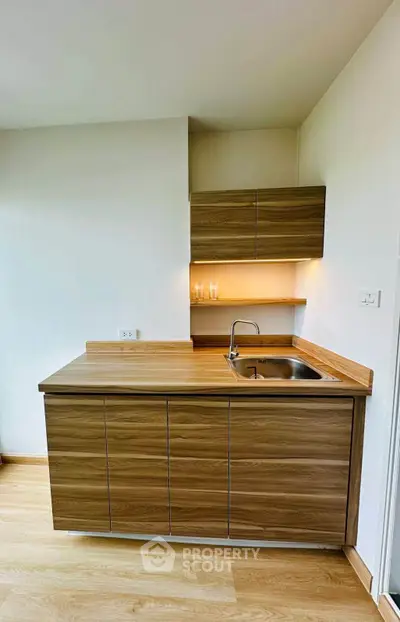 Modern kitchen with sleek wooden cabinetry and built-in sink, perfect for contemporary living.