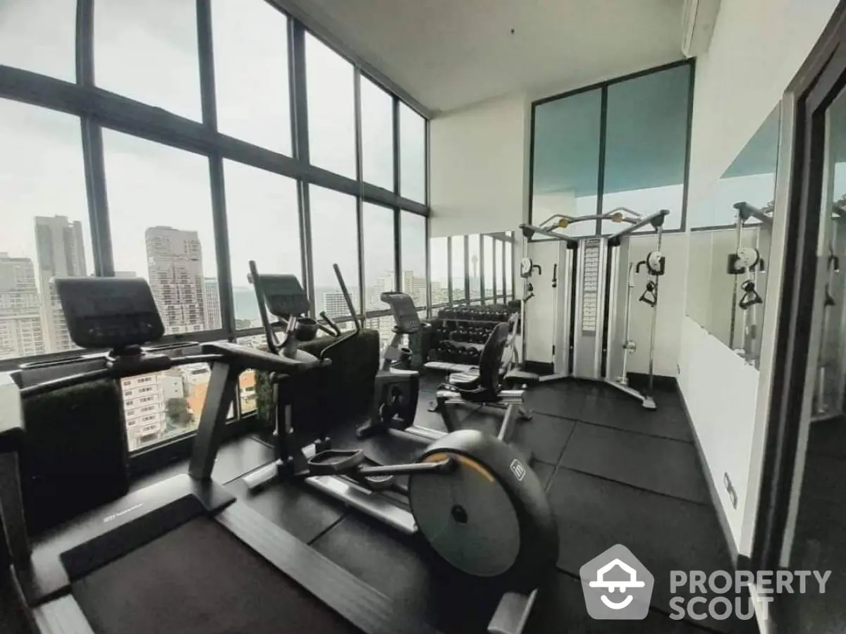 Modern high-rise gym with panoramic city views and state-of-the-art fitness equipment.