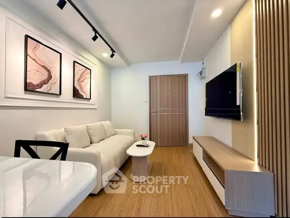 Modern living room with sleek design, featuring a comfortable sofa, wall-mounted TV, and stylish decor.