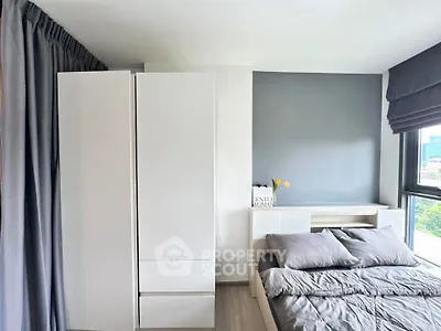 Modern bedroom with sleek white wardrobe and cozy bed near large window.