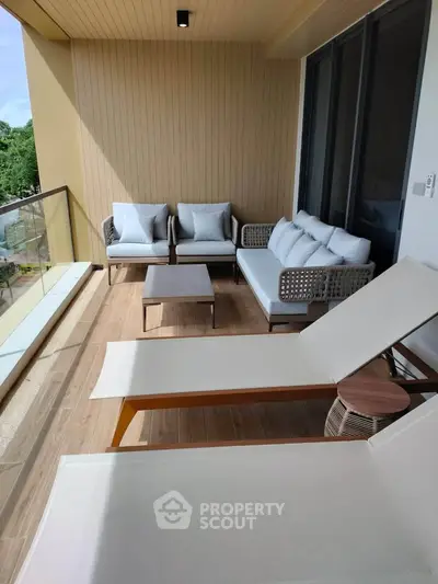 Spacious balcony with modern outdoor furniture and scenic view, perfect for relaxation.