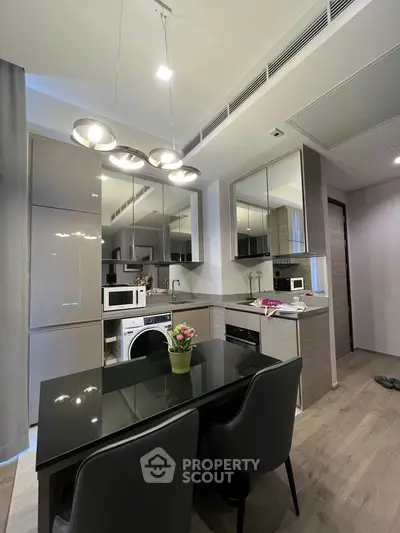 Modern kitchen with sleek cabinetry, dining table, and built-in appliances in a stylish apartment.