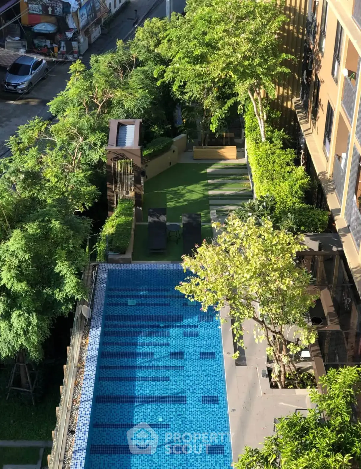 Stunning aerial view of a modern building with a sparkling pool and lush garden area.