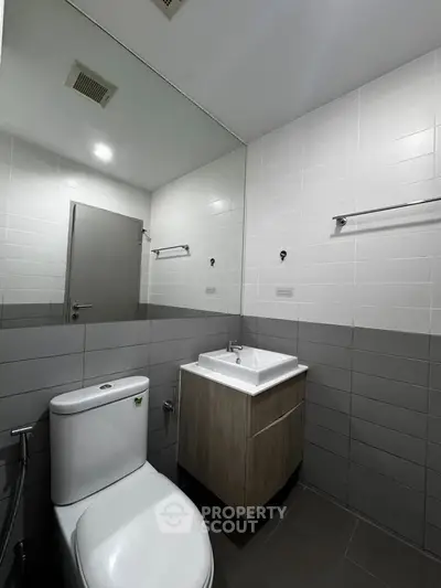 Modern bathroom with sleek design, featuring a wall-mounted sink and large mirror.