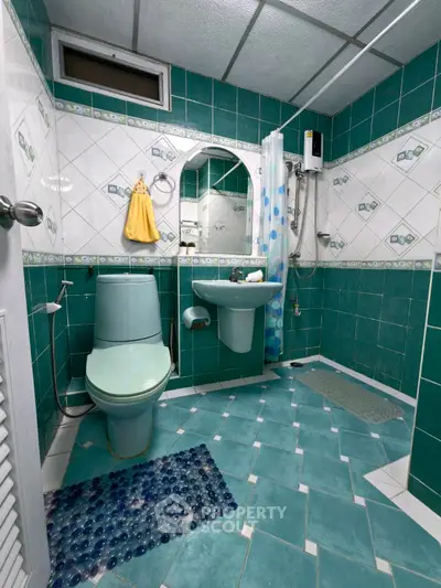 Charming turquoise-tiled bathroom with modern fixtures and shower, ideal for a cozy home.