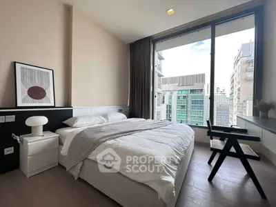 Modern bedroom with large window offering stunning city view, featuring stylish decor and cozy ambiance.