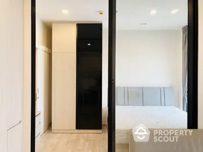 Contemporary bedroom with sleek built-in wardrobe and large mirror reflecting a comfortable bed, ideal for modern living.