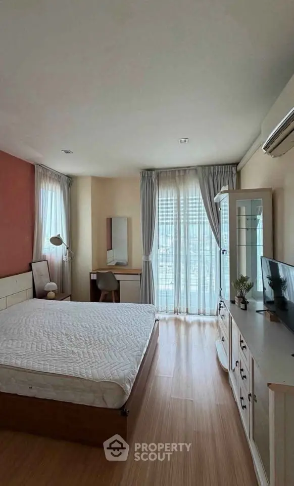 Spacious bedroom with natural light, modern furniture, and elegant decor in a stylish apartment.