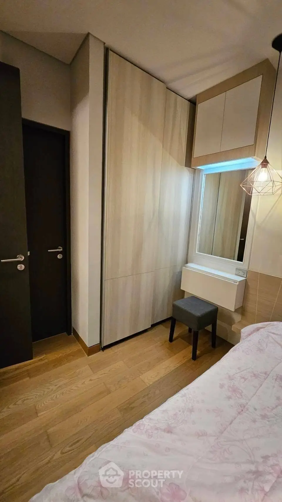 Cozy bedroom with wooden flooring and built-in wardrobe, featuring a stylish vanity area.