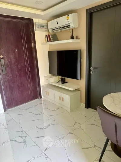 Modern living room with marble flooring and wall-mounted TV, featuring sleek furniture and air conditioning.