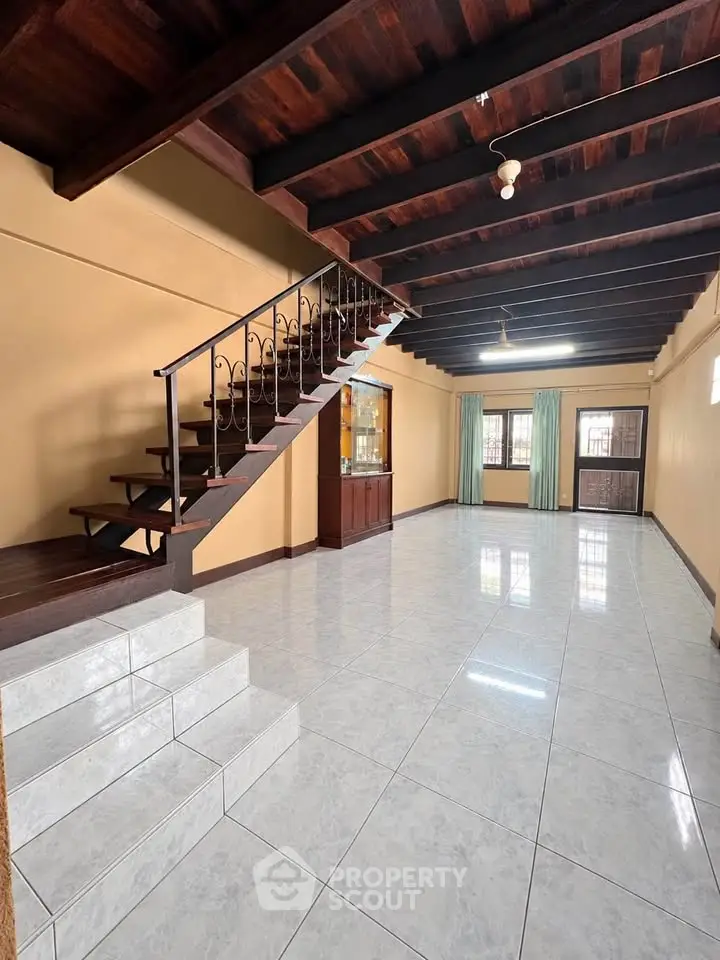 Spacious living room with wooden ceiling and staircase, ideal for family gatherings.