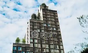 Modern high-rise building with unique architectural design and rooftop greenery.