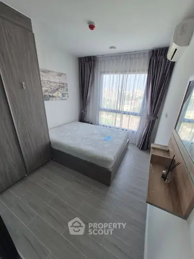 Modern bedroom with large window and stylish decor in a contemporary apartment.