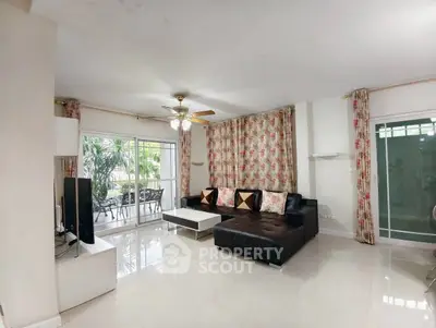 Spacious living room with modern decor and large windows opening to a garden view.