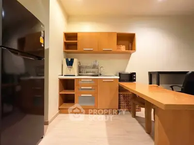 Modern kitchen with wooden cabinets, fridge, and microwave in cozy apartment.
