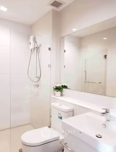 Modern bathroom with sleek fixtures and elegant design, featuring a spacious shower and contemporary sink.