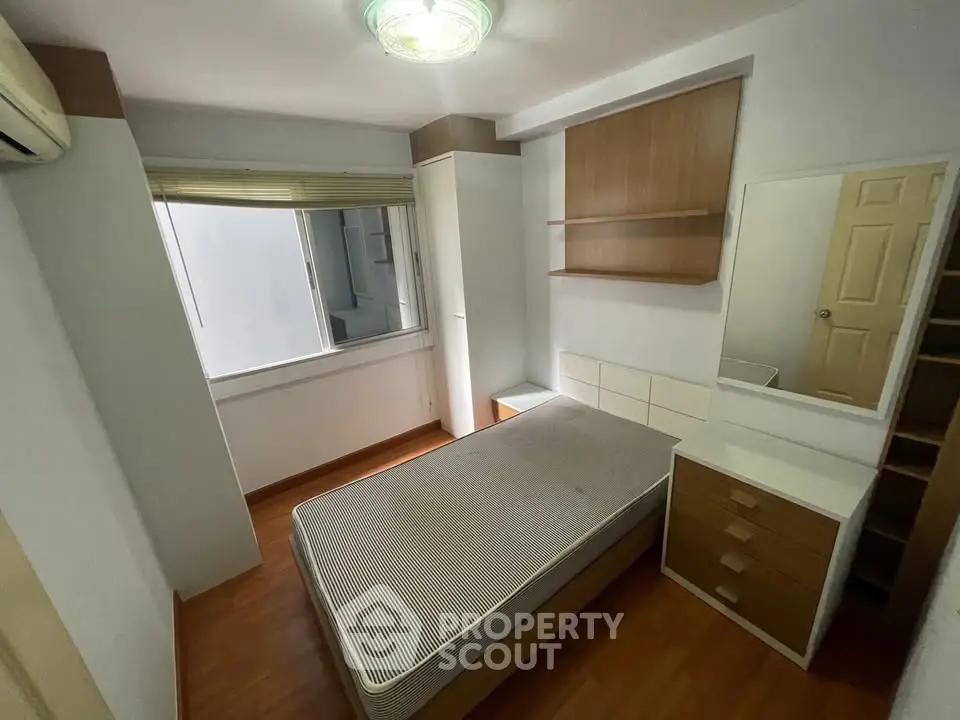Cozy bedroom with wooden flooring and built-in storage, perfect for modern living.