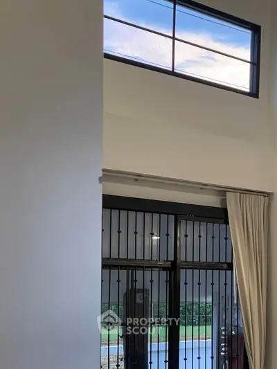 Modern interior with high ceiling and large windows offering natural light