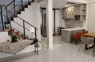 Modern open-plan kitchen and dining area with stylish staircase and contemporary lighting.