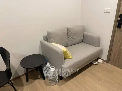 Cozy living room corner with a modern gray sofa and stylish side table, perfect for relaxation.