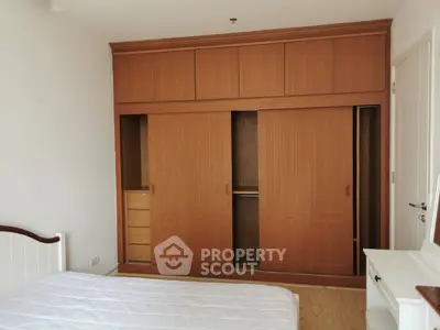Spacious bedroom with large wooden wardrobe and cozy bed setup