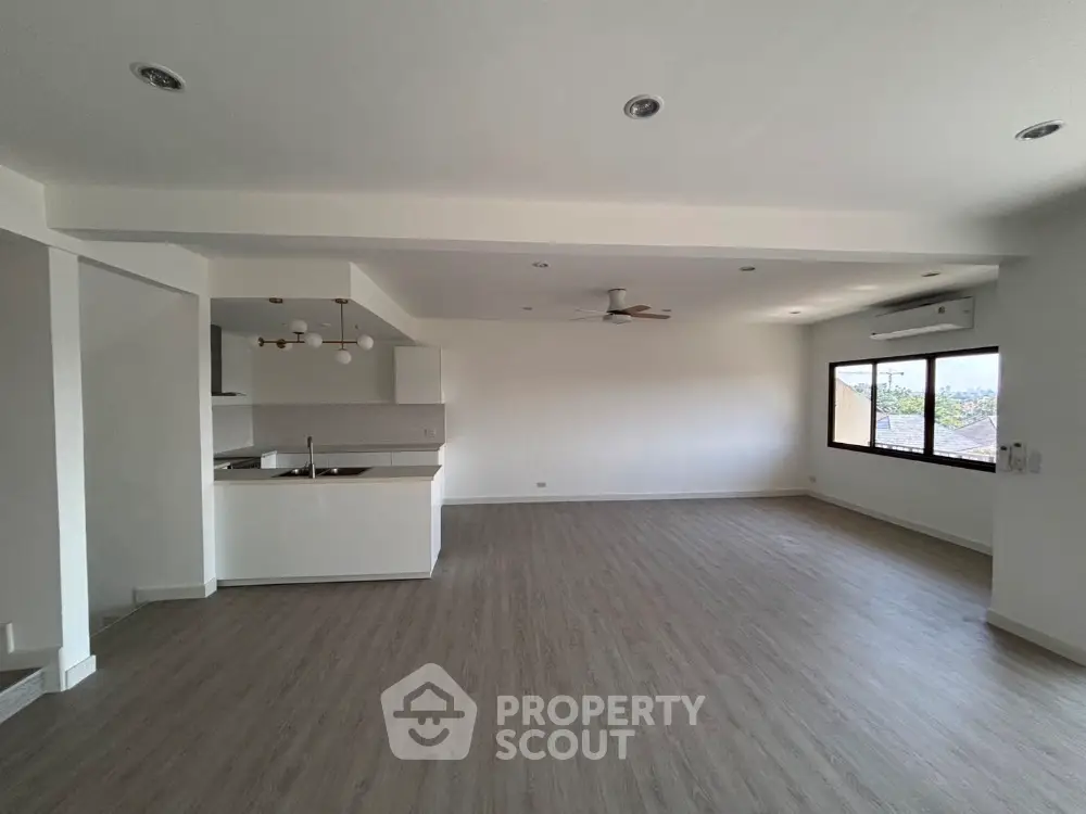 Spacious open-plan living room with modern kitchen and large windows