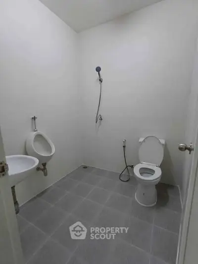 Minimalist bathroom with shower, toilet, and urinal in a modern real estate property.