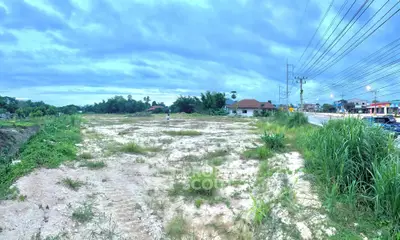 Expansive vacant land with potential for development, surrounded by lush greenery and accessible roadways.