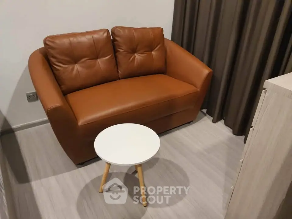 Cozy living room with brown leather loveseat and small round table, perfect for relaxation.