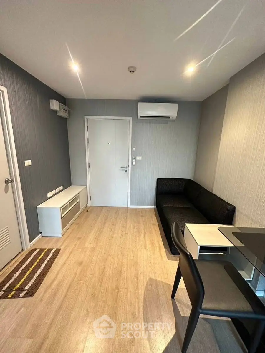 Modern living room with sleek furniture and wooden flooring, featuring air conditioning units.