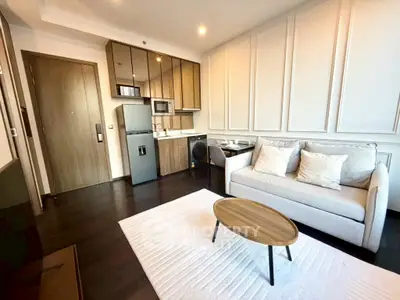 Modern living room with sleek kitchen, cozy sofa, and stylish decor in a contemporary apartment.