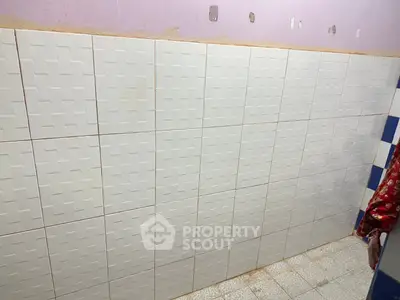 Simple tiled bathroom wall with textured white tiles and purple upper wall.