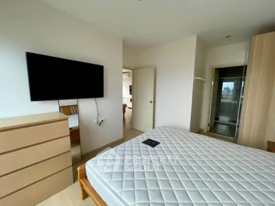 Spacious bedroom with modern furnishings and wall-mounted TV in a stylish apartment.