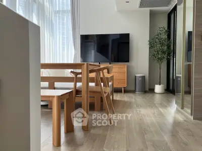 Modern living room with wooden furniture and large TV, featuring floor-to-ceiling windows.