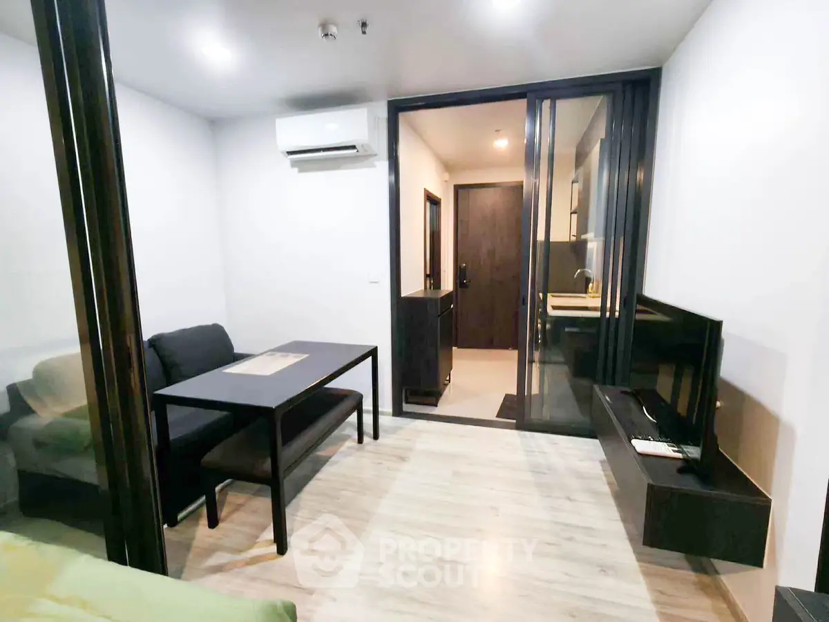 Modern living room with sleek furniture and glass partition in a contemporary apartment.