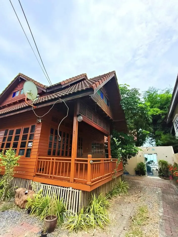 Charming wooden house with a cozy porch and lush greenery, perfect for serene living.