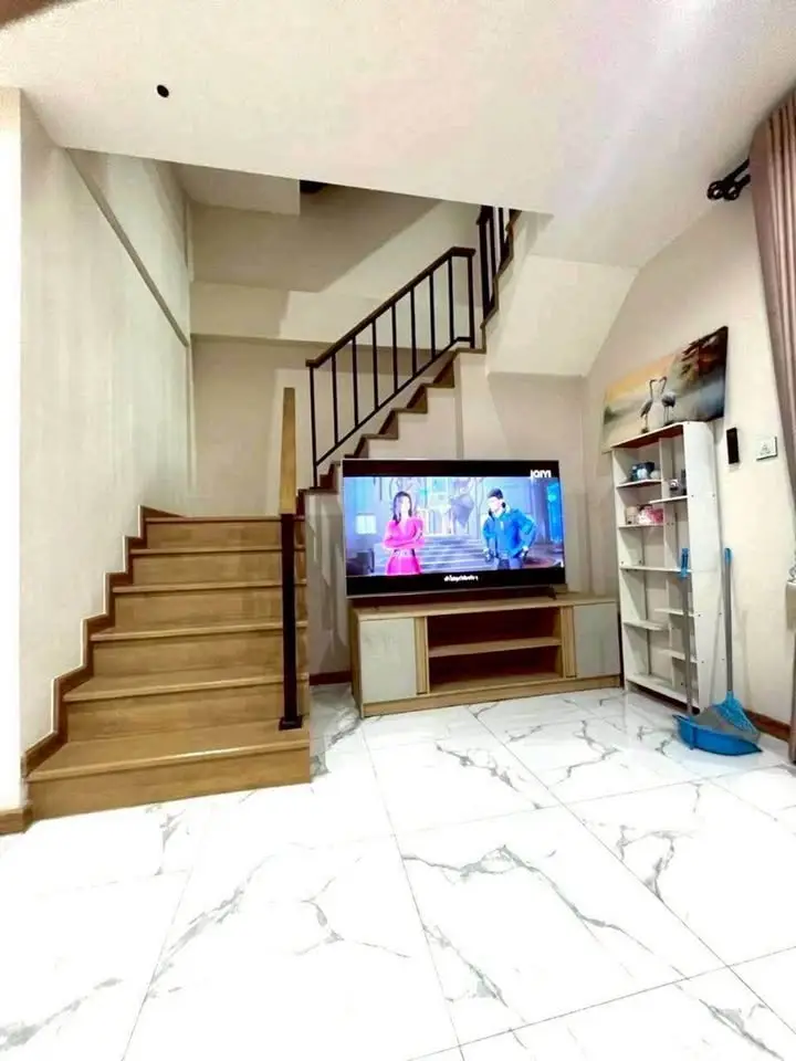 Stylish modern living room with staircase and TV, featuring elegant marble flooring.