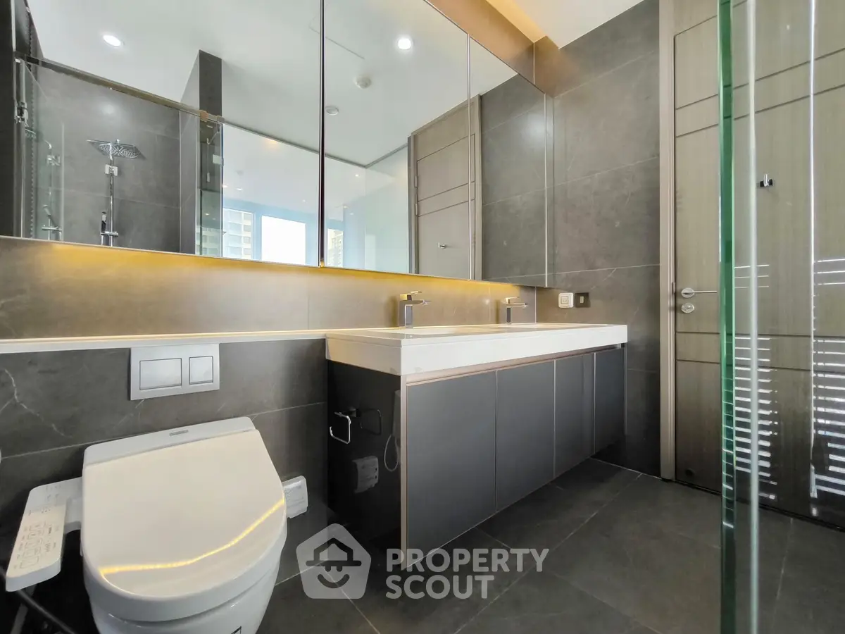 Luxurious modern bathroom with sleek fixtures and large mirror in high-end apartment.