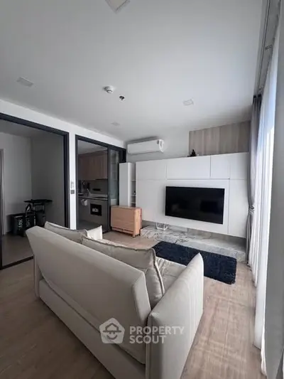 Modern living room with sleek design and wall-mounted TV, featuring open layout and natural light.