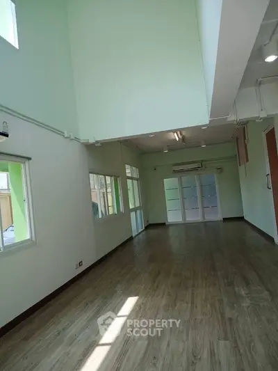 Spacious open-plan living area with high ceilings and large windows, perfect for modern living.