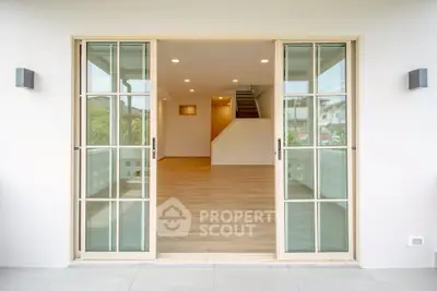 Spacious modern living room with sliding glass doors and wooden flooring, perfect for natural light and open living.