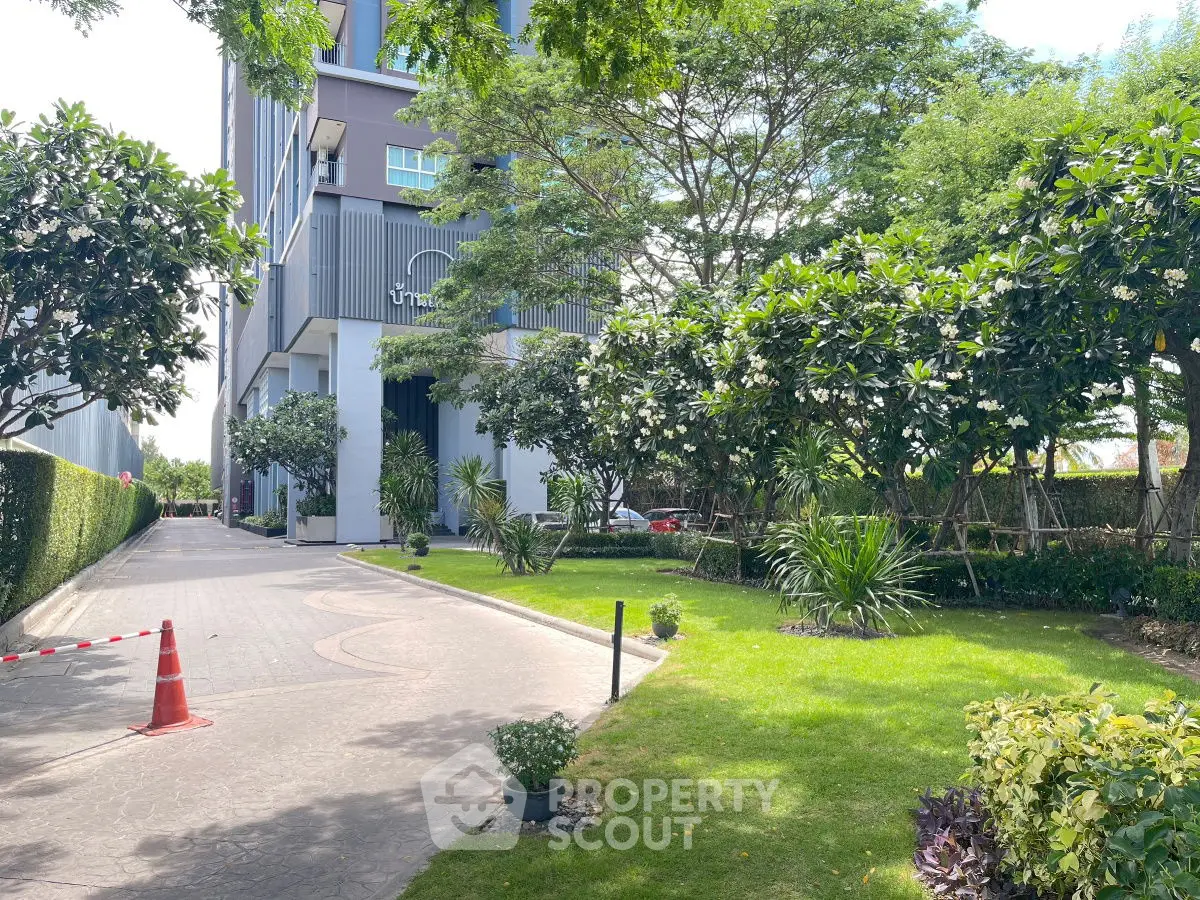Luxurious building entrance with lush green garden and modern architecture.