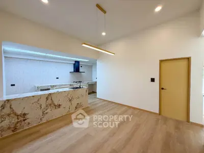 Modern open-layout kitchen with marble countertops and wooden flooring