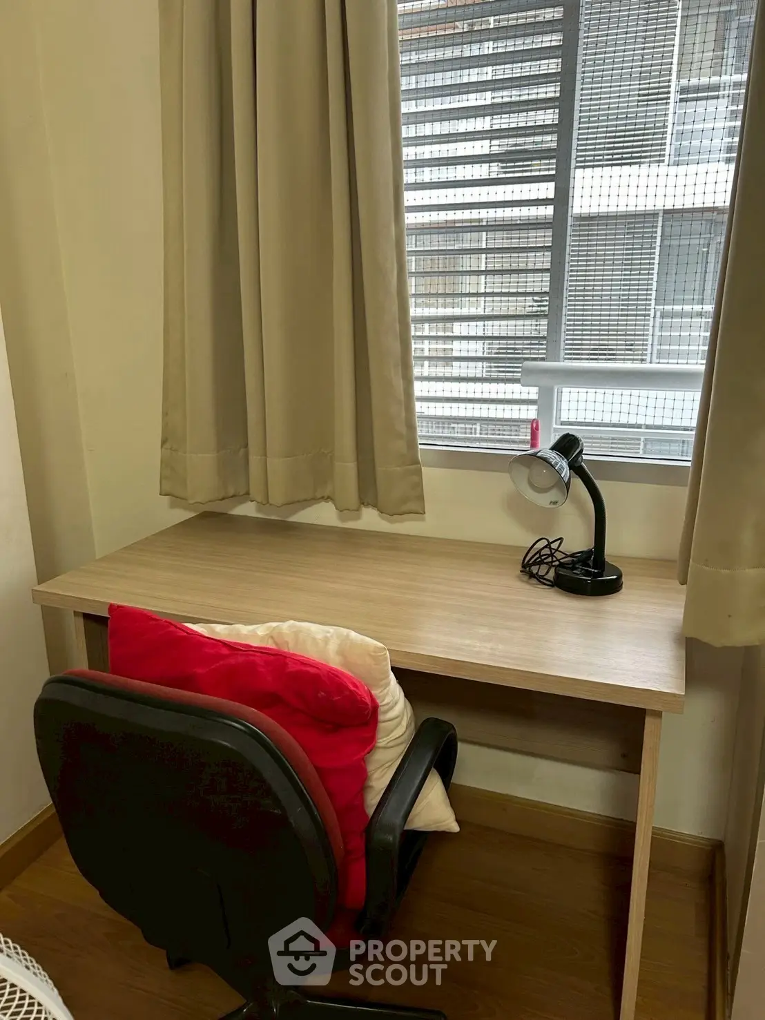 Cozy study nook with desk, chair, and lamp by window in modern apartment.