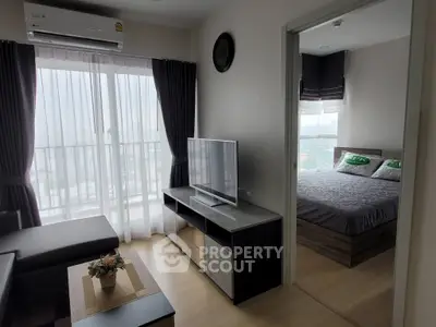 Modern apartment living room with TV and bedroom view, featuring stylish decor and natural light.