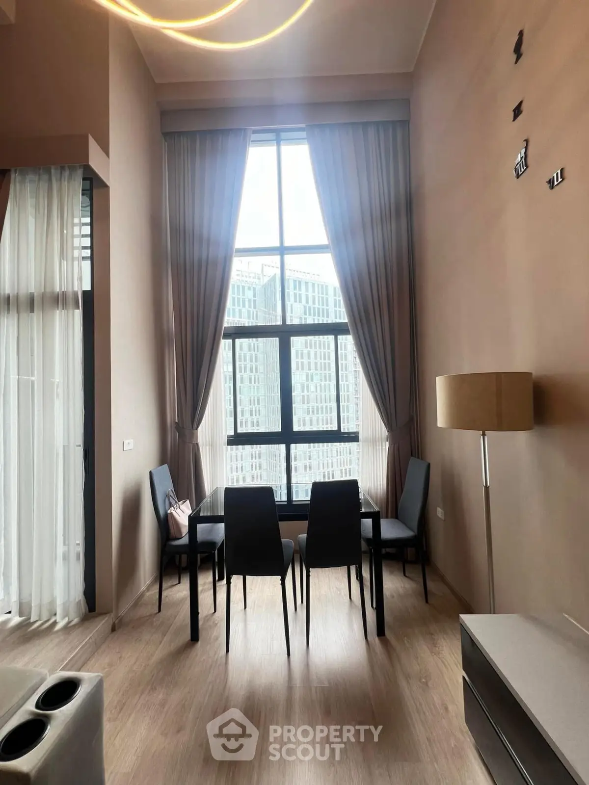 Spacious modern living room with high ceilings and large window offering city views.